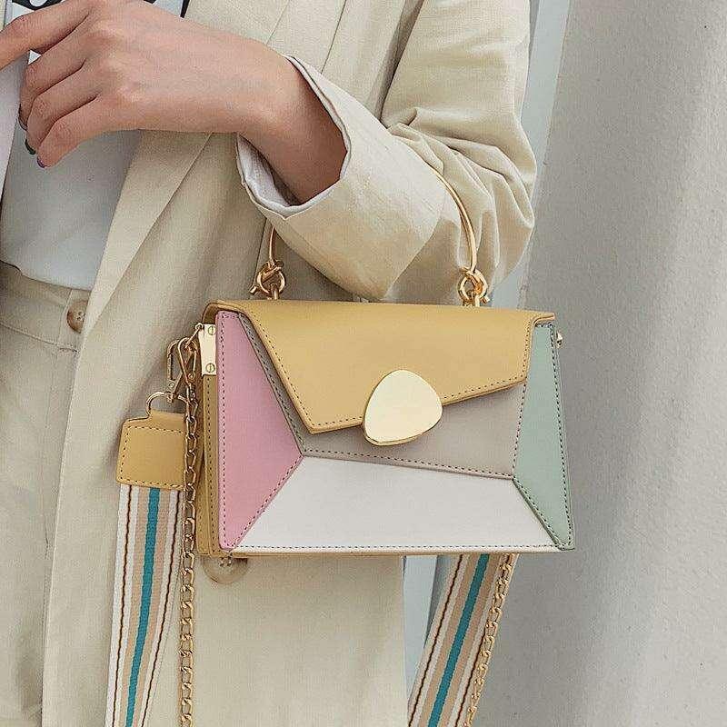 A bag designed in soft tones with a shoulder strap and an elegant carrying handle.
